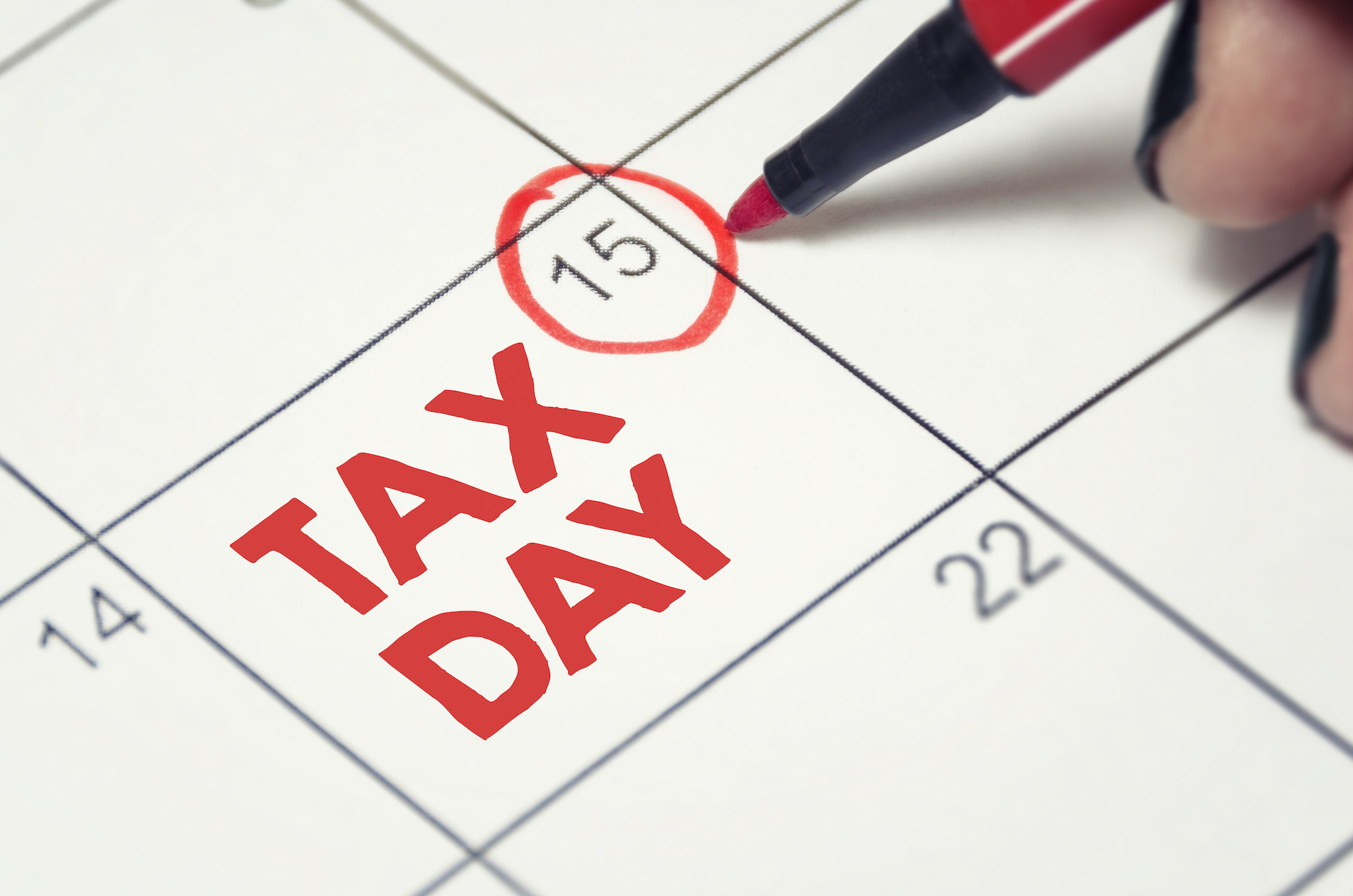 circle the 15th date on a calendar with the words "Tax Day" written in bold red text
